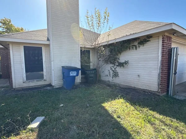 Before: back of the house with worn siding and trim in Lancaster, TX