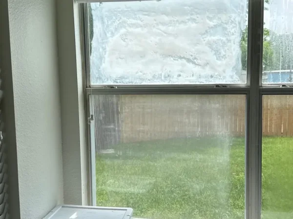 Before: fogged window pane seen from inside the home in Garland, TX