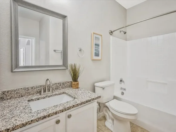 Before: guest bathroom with granite vanity top and white tub surround in Dallas, TX