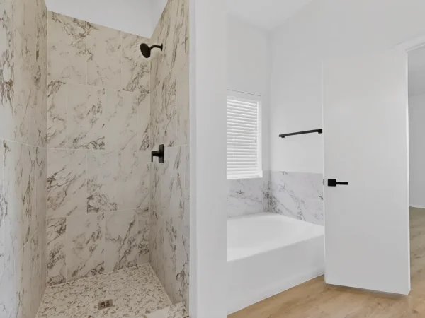 After: primary bathroom with a new tiled shower and tub in DeSoto, TX