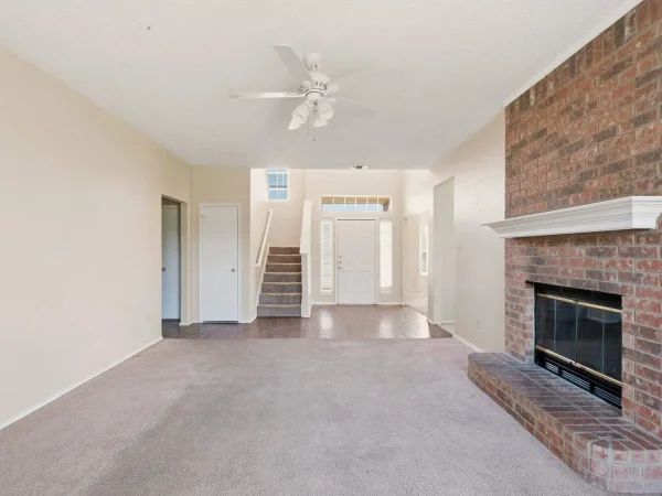 Before: living room with a red brick fireplace and carpet in DeSoto, TX